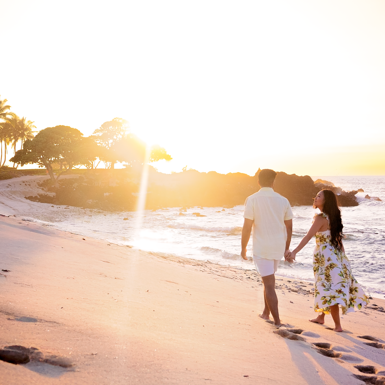 Couple walking hand in hand on a beach at sunset with gentle waves lapping the shore Big Island family photographer during sunset in Kona, H